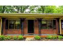 Home exterior showcasing charming brickwork, decorative iron porch supports, and manicured landscaping at 6470 Sherwood Trl, Austell, GA 30168