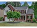 Charming two-story brick home featuring a black front door, a covered front porch, and manicured landscaping at 3958 Windgrove Xing, Suwanee, GA 30024