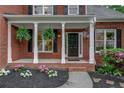 Inviting covered front porch with white columns and black shutters, and blooming flowers at 3958 Windgrove Xing, Suwanee, GA 30024