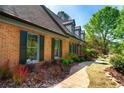 A brick home featuring dark shutters, complemented by manicured landscaping and a charming walkway at 3485 Aubusson Trce, Johns Creek, GA 30022