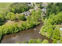 Aerial view of a home with a pool on a lake surrounded by lush trees, a dock, and other homes nearby at 109 Hawks Bnd, Canton, GA 30115