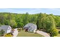 Aerial view of a two-story home with a lush lawn, driveway, and detached two-car garage, surrounded by mature trees at 109 Hawks Bnd, Canton, GA 30115
