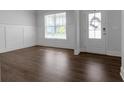 Bright living room with hardwood floors, white wainscoting, and a door with a decorative wreath at 9913 Stretford Rd, Douglasville, GA 30135