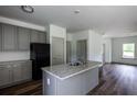 Bright kitchen with gray cabinets, stainless steel appliances, island with granite countertops, and vinyl floors at 358 Forkview Dr, Lawrenceville, GA 30044