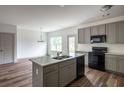 Modern kitchen with gray cabinets, black appliances, and granite countertops, seamlessly flows into dining area at 358 Forkview Dr, Lawrenceville, GA 30044