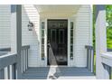 Inviting entryway featuring a black front door, sidelights, and classic sconce at 5135 Gable Ridge Way, Sugar Hill, GA 30518