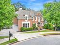 Beautiful brick home featuring a well-maintained lawn, side-entry garage, and mature trees at 515 Old Chartwell Xing, Alpharetta, GA 30022