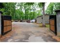 Open wooden gate reveals expansive driveway with multiple vehicles and equipment on the property at 208 Holiday Way, Carrollton, GA 30116