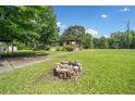 Wide view of the home displaying the lawn and exterior featuring a cozy fire pit and surrounding trees, perfect for outdoor enjoyment at 170 White Rose Ln, Temple, GA 30179