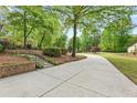 Long, concrete driveway leading to a charming home with lush landscaping and mature trees at 2488 Fontainebleau Dr, Dunwoody, GA 30360