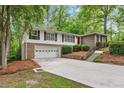 Lovely exterior view of home with driveway, red front door, brick facade, and lush, mature landscaping at 2488 Fontainebleau Dr, Dunwoody, GA 30360
