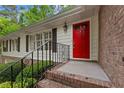 Close up of a bright red front door with sidelight, black iron railing, and brick steps at 2488 Fontainebleau Dr, Dunwoody, GA 30360