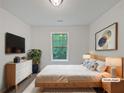 Staged bedroom with queen bed, tv, dresser, bedside tables, neutral decor and large window at 7155 Homestead Rd, Rex, GA 30273