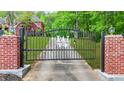 A black iron gate with brick columns adds charm to the property entrance at 2498 Highway 212, Covington, GA 30016