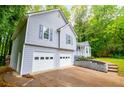 Side view of the house with gray siding, white garage doors, and steps up to the front porch at 4822 Westbourne Dr, Powder Springs, GA 30127