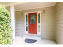 Close-up of a vibrant red front door with decorative glass, framed by sidelights and elegant sconces at 2055 Springer Walk, Lawrenceville, GA 30043