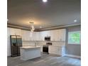 Modern kitchen with an island, stainless steel appliances, white cabinets, and gray floors at 3368 Bonnes Ct, Ellenwood, GA 30294