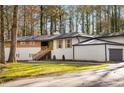 Side view of the home's exterior displaying the garage, painted stucco, black trim, and manicured front lawn at 2019 Emerald Dr, Jonesboro, GA 30236