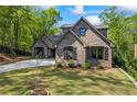 Brick home featuring a well-kept lawn, complemented by trimmed bushes and a three-car garage at 1188 Woodtrace Ln, Auburn, GA 30011
