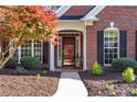 Inviting front entrance with a red door, manicured landscaping, and brick facade at 1315 Badingham Dr, Cumming, GA 30041
