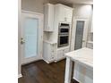 A view of the white kitchen with double ovens, pantry, and a door leading to the outside, complemented by hardwood floors at 169 Long Dr, Marietta, GA 30060