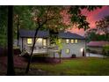 Backyard view showcases the home's rear deck, grassy lawn, and wooded surroundings at twilight at 2152 Tourney Dr, Marietta, GA 30062