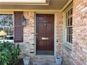 Inviting brick home entrance featuring a classic wood door and decorative window shutters at 3358 Stonecrest Ct, Atlanta, GA 30341