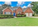 Attractive brick home with manicured landscaping, double garage and bright blue door at 4512 Evan Ct, Hoschton, GA 30548