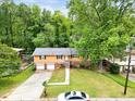 Aerial view of house featuring a two-car garage, surrounded by lush greenery, complemented by a well-manicured lawn at 1563 Greenwood Dr, Norcross, GA 30093
