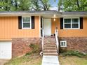 Front entrance featuring a brick foundation, siding, and inviting stairway leading to the front door at 1563 Greenwood Dr, Norcross, GA 30093