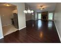 Open-concept living room featuring hardwood floors, a fireplace, and a view of the kitchen at 1231 Providence Way, Lawrenceville, GA 30046