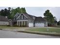 Two-story home featuring stone and siding and a three-car garage with extra parking on a wide concrete driveway at 15 Worthington Dr, Villa Rica, GA 30180