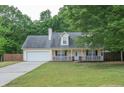 Inviting home featuring a covered porch, attached garage, and lush green yard at 420 Bear Cub Path, Social Circle, GA 30025