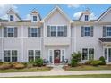 Attractive townhome features gray siding, neat landscaping, a red front door, and shaded seating area at 1702 Prospect Way, Conyers, GA 30094