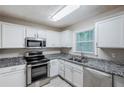 Modern kitchen features stainless steel appliances, granite countertops, white cabinets, and tiled floors at 2796 Green Trail Dr, Atlanta, GA 30349