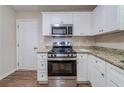 Updated kitchen features a stainless steel range, microwave, granite countertops, and white cabinets at 3497 Glensford Dr, Decatur, GA 30032