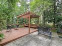 Cozy wooden deck and patio area surrounded by lush trees, with bench seating and other furniture at 3220 Stoney Acres Nw Dr, Kennesaw, GA 30152