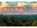 View of the city skyline in the distance, beyond a lush green forest, under a sky filled with colorful clouds at 4100 Paces Se Walk # 4306, Atlanta, GA 30339