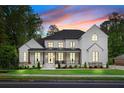 Beautiful modern farmhouse at sunset featuring white siding, black trim, and a spacious front porch at 575 Indian Hills Pkwy, Marietta, GA 30068