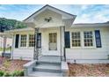 Close up of the home's front, featuring a white exterior with black shutters and decorative iron porch supports at 1236 Stone Mountain Lithonia Rd, Lithonia, GA 30058