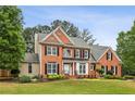 Beautiful two-story brick home with a well-maintained lawn and classic architectural details at 205 Devon Downs Pl, Alpharetta, GA 30005