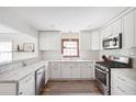 Kitchen features white cabinets, stainless steel appliances, a subway tile backsplash, and new flooring at 4527 Sims Ct, Tucker, GA 30084