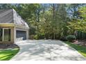 Wide concrete driveway leading to attached garage with ample parking space and mature trees at 1585 Lazy River Ln, Sandy Springs, GA 30350