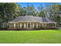 Beautiful single story brick home with lush green lawn, mature trees and a well manicured landscape at 1585 Lazy River Ln, Sandy Springs, GA 30350
