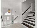 Inviting foyer with staircase and a stylish pendant light fixture above the door with decorative glass at 101 Saddlehorn Ct, Woodstock, GA 30188