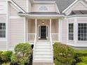Inviting front porch with white railings and a black front door, surrounded by lush greenery at 1633 Clifton Downs Ct, Kennesaw, GA 30144