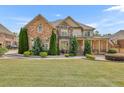 Beautiful two-story home featuring a brick facade, manicured lawn, and inviting covered porch at 2932 Springbluff Ln, Buford, GA 30519