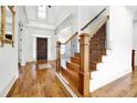 Elegant foyer featuring hardwood floors, wooden staircase, and a decorative front door at 2932 Springbluff Ln, Buford, GA 30519