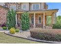 Inviting front yard landscaping with gravel, manicured shrubs, and covered porch with brick columns at 2932 Springbluff Ln, Buford, GA 30519