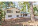 View of a yellow and white exterior elevation, complete with a two-car garage, set against a backdrop of lush woodland at 4639 Hardwood Rd, Stone Mountain, GA 30083